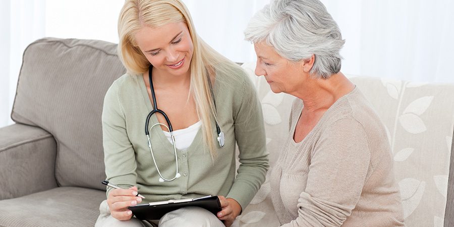 A clinician talks through notes on a clipboard with an older woman